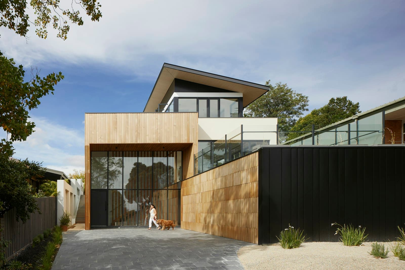 Contemporary house with a finished stone-paver courtyard, planting beds, and dark wood fencing.
