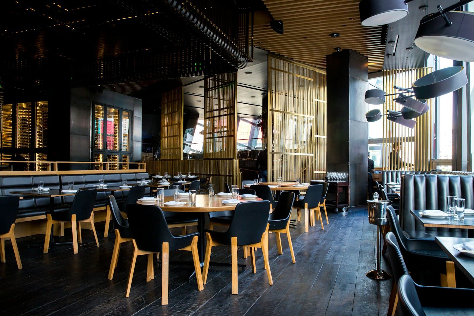 Intimate dining room with dark chairs, oak tables, gold screens, and places set for evening service.